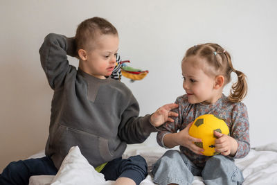 Boy playing with toy while sitting on sofa at home