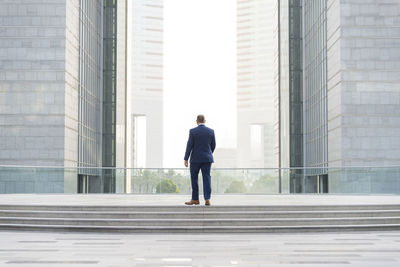 Rear view of man walking against building