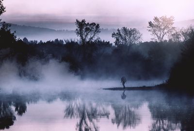 Man standing by lake against sky