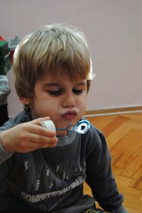 Close-up of cute boy blowing bubble while sitting at home