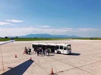 People at airport runway against sky