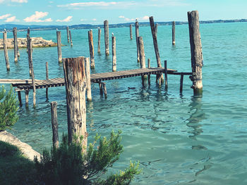 Wooden posts in sea against sky