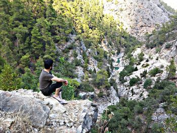 Rear view of man climbing on cliff against mountain