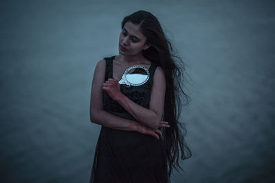 Young woman wearing mask standing against the wall