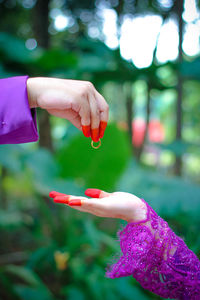 Cropped image of groom giving ring to bride at forest