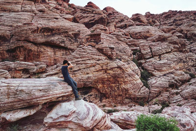 Low angle view of rocks on cliff against mountains