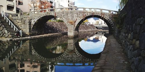 Arch bridge over river against buildings