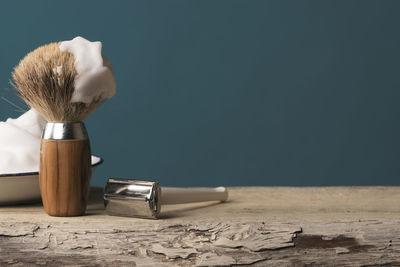 Close-up of shaving equipment on table against blue background