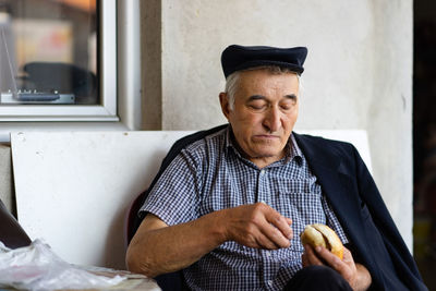 Portrait of smiling man eating bread while sitting at home