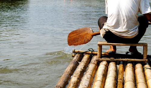 Low section of man on wooden raft in lake