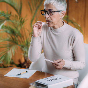 Midsection of woman holding paper while sitting on table