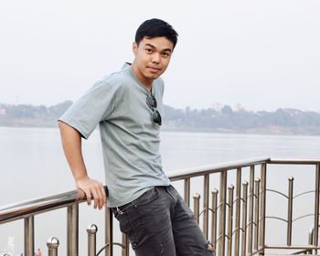 Portrait of young man standing against sea