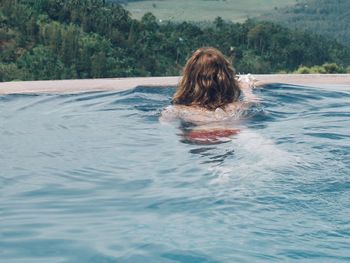 Rear view of woman swimming in pool