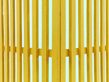 Corner of yellow wooden fence isolated on light blue background