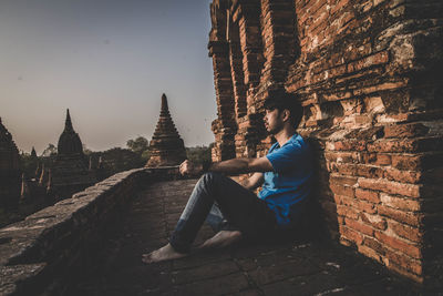 Side view of man sitting outside temple