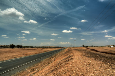 Road amidst field against sky