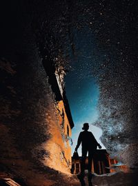 Rear view of silhouette woman standing against sky on the puddle