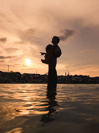 Silhouette man standing on beach against sky during sunset