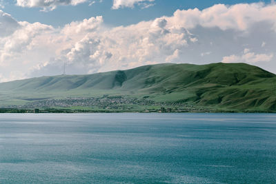 Scenic view of sea by mountain against sky