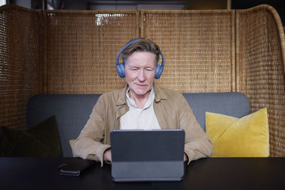 Senior man with headphones using tablet