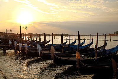 Boats moored in canal at sunset