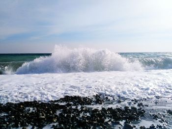 Waves splashing on sea against sky