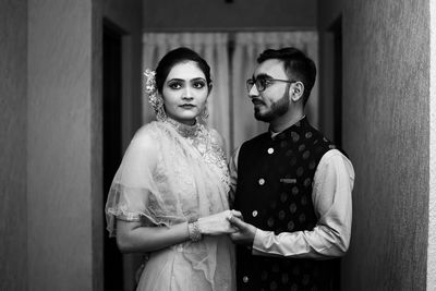 Portrait of young couple standing against wall