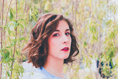 Portrait of beautiful young woman against plants