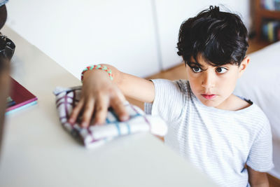 High angle view of boy cleaning cabinet in at home