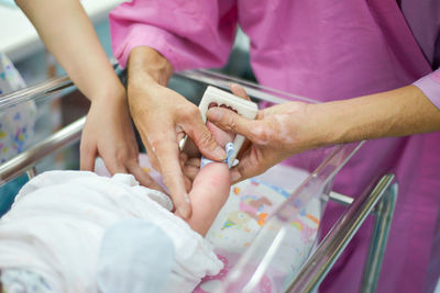 Midsection of doctors holding leg of newborn baby in hospital