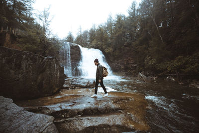 Full length of man standing on rock against waterfall