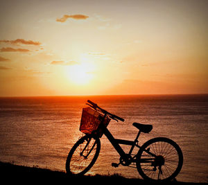 Bicycle parked at beach during sunset