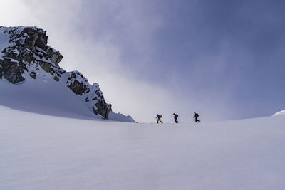 People skiing on snowcapped mountain against sky