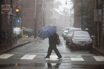 Man walking on wet street in city during rainy season