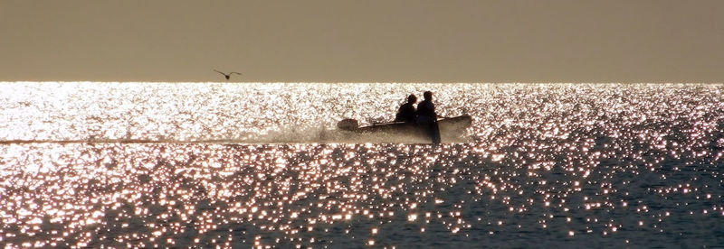 Silhouette of two fishermen in the boat in sunset, michigan lake, il usa