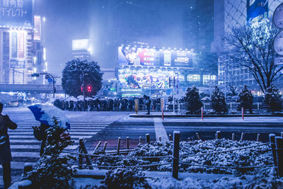 Snow covered city against sky at night