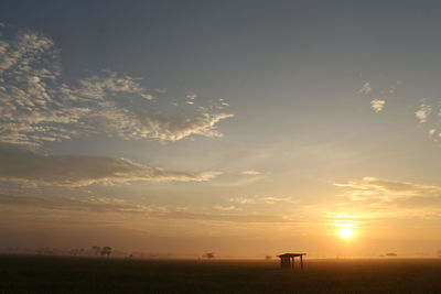 Scenic view of silhouette field against sky during sunset