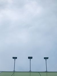 Low angle view of street light against sky on green