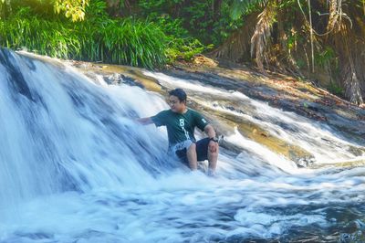 Man surfing in waterfall in forest