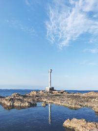 Lighthouse amidst sea and buildings against sky