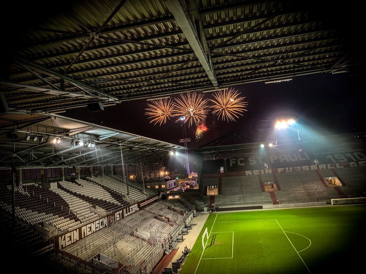 sport, night, illuminated, stadium, architecture, ceiling, lighting equipment, team sport, arts culture and entertainment, soccer, playing field, low angle view, incidental people, group of people, competition, soccer field, indoors, real people, light, spectator, floodlit