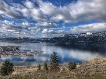 Scenic view of lake by mountains against sky