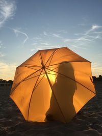 Tent on beach against sky during sunset