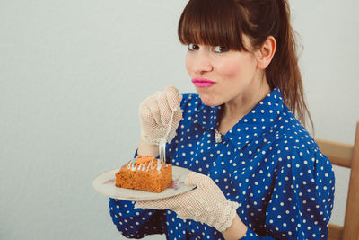 Portrait of young woman holding ice cream against white background