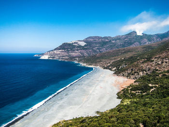 Scenic view of sea and mountains against blue sky