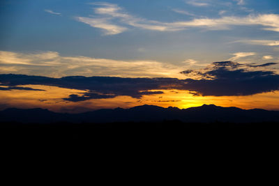 Scenic view of silhouette mountains against orange sky