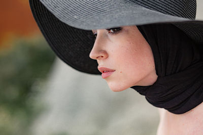 Close-up of thoughtful woman wearing black hat