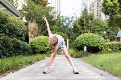 Rear view of woman walking on footpath by road