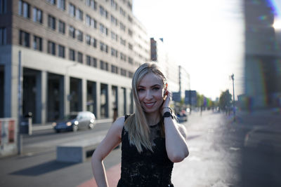 Portrait of smiling young woman standing on street in city