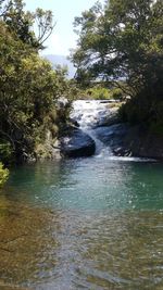 Scenic view of waterfall in forest against sky